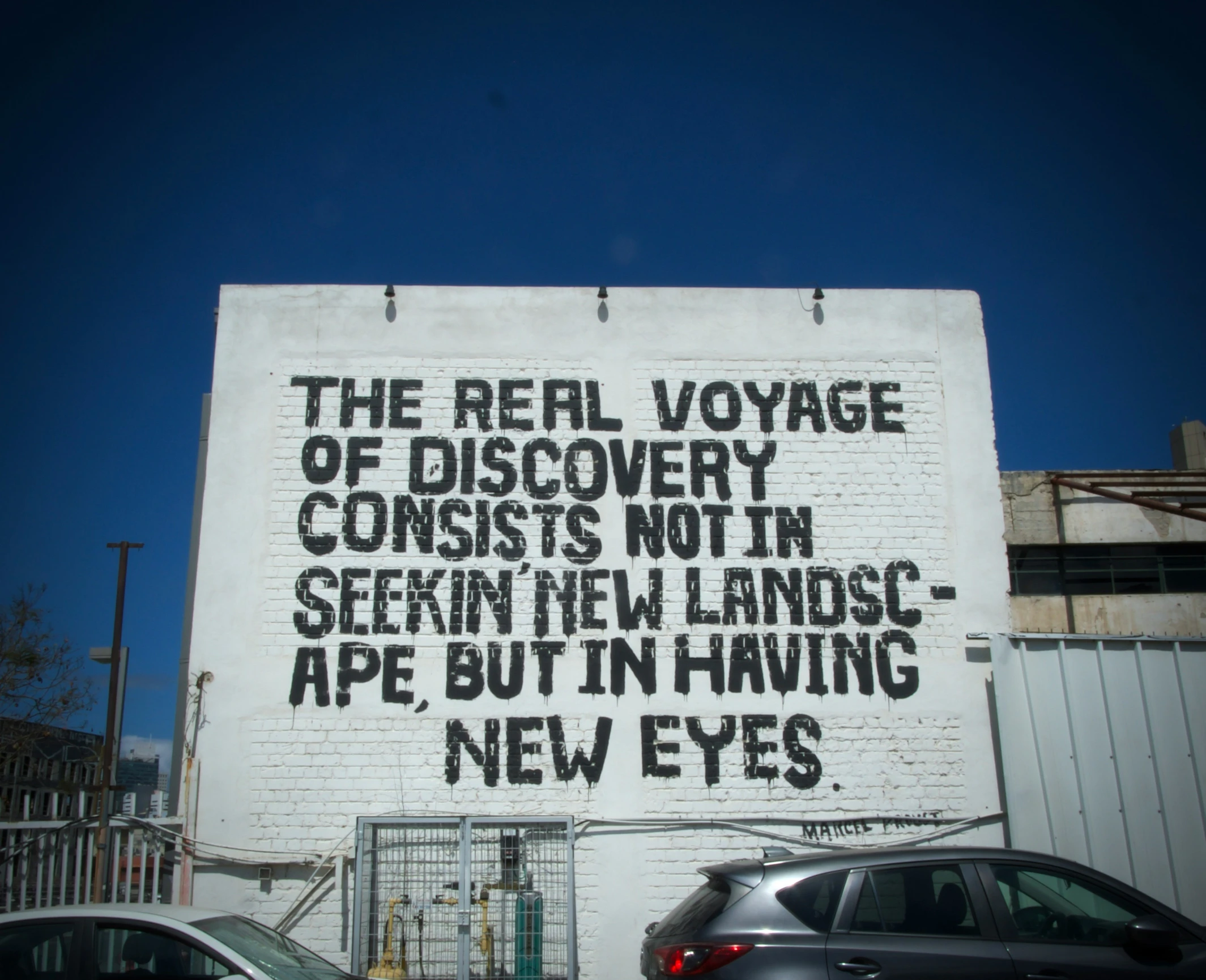 a graffiti on the side of a building, reads the revival voyage of discovery consists not in several seen, i'm