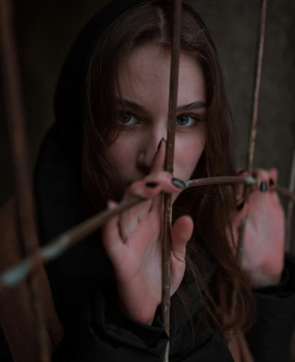 a woman is standing behind bars with a sad look on her face