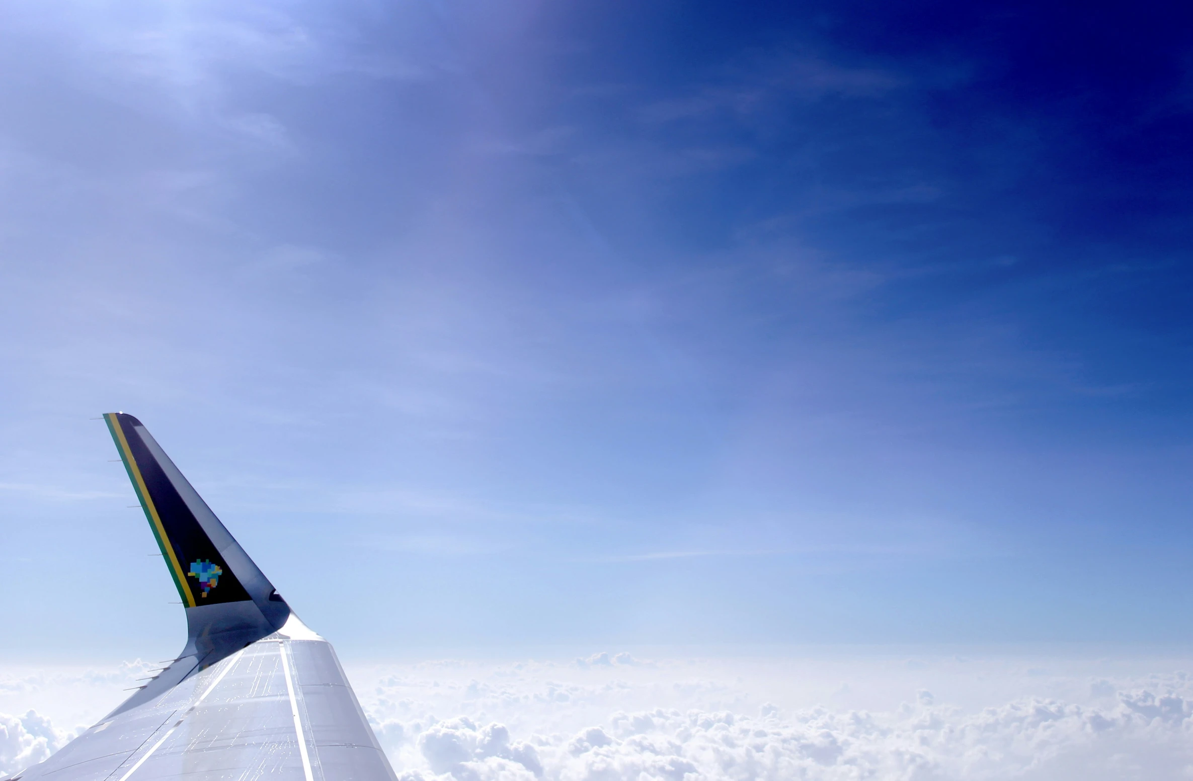 a plane wing flying through the blue sky