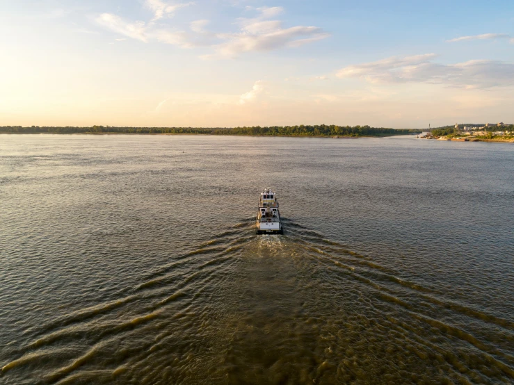 a boat moving along the water while a light house stands in the distance