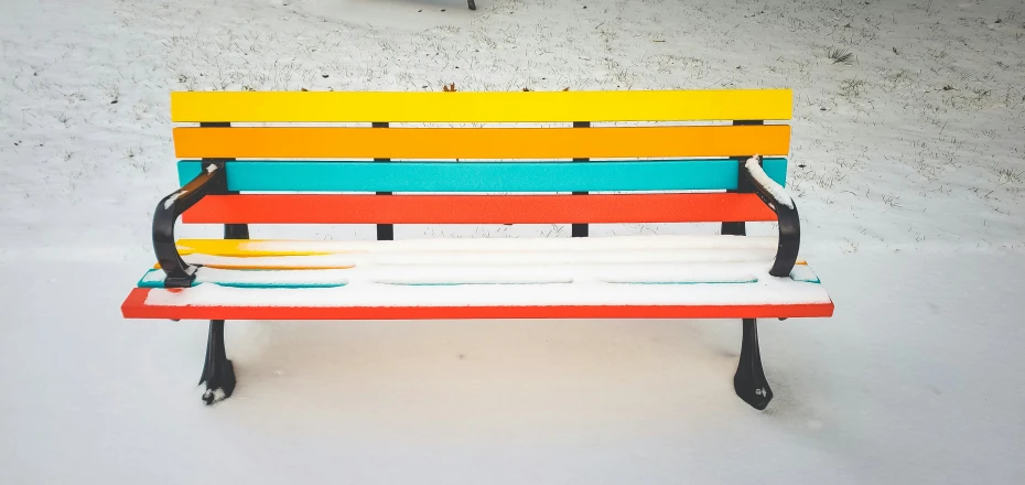 a colorful bench sitting on a snow covered ground