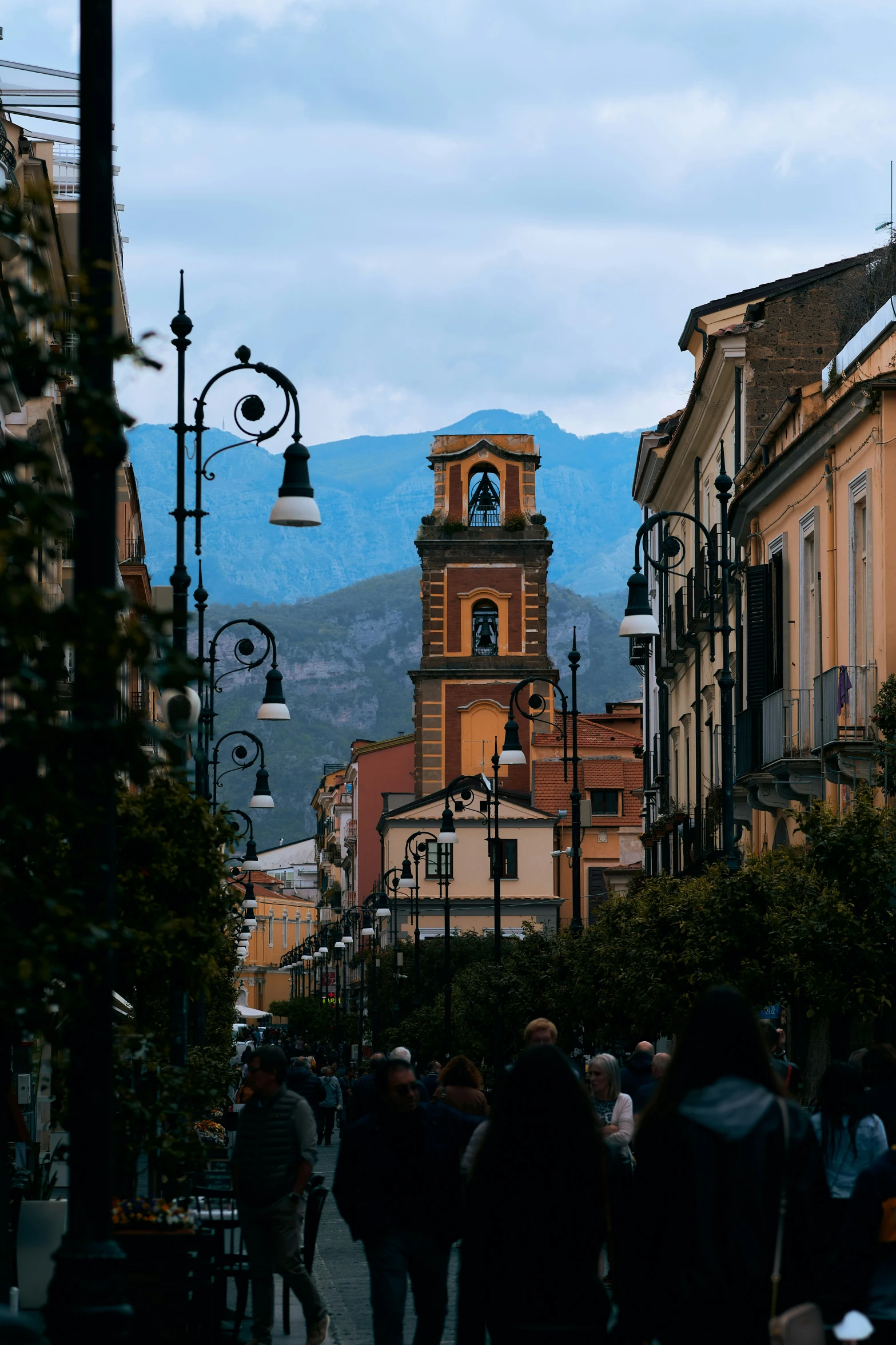 a group of people walking down a road under a tower