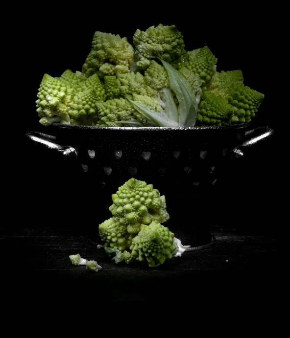 broccoli in a black bowl sitting on a table