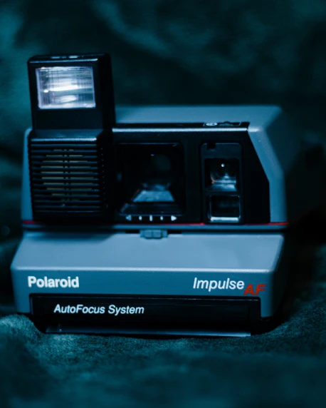 a polaroid camera with two electronic devices attached to it