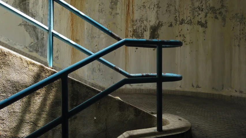 a stairway next to a cement wall that has peeling paint