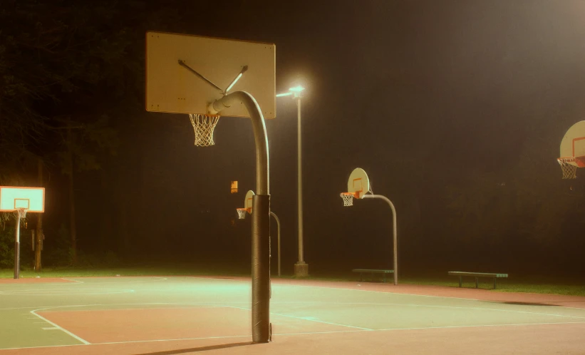 a basketball court in the night with street lights and basketball hoop