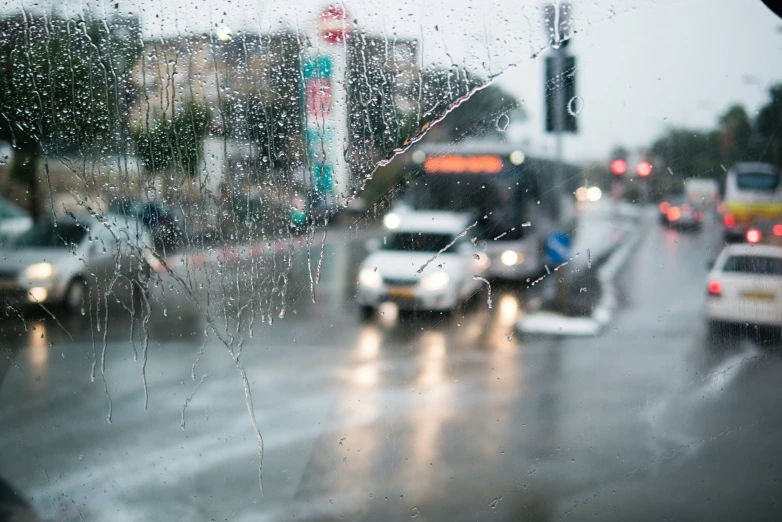 rain falls on a wet window at a city intersection