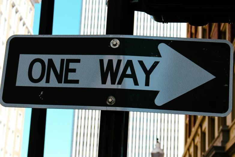 one way sign posted on the pole with buildings in the background