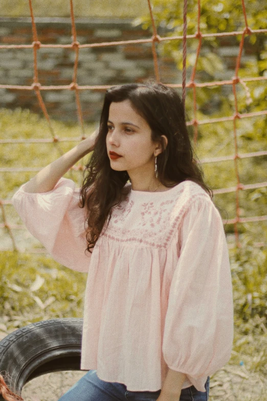 a little girl wearing a pink top and jeans standing next to a tire