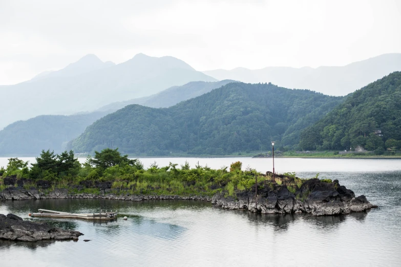 the mountains are covered in thick fog as a bird flies over water