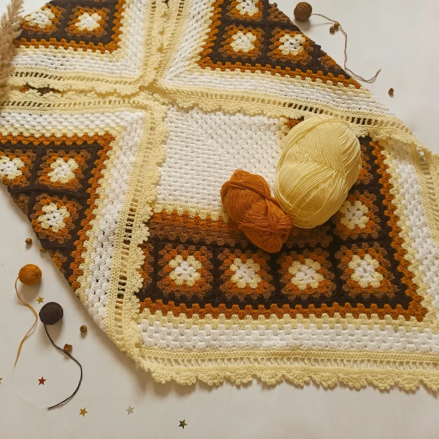 a yellow ball of yarn sits on a blanket