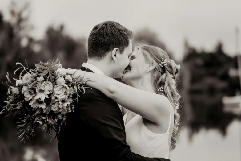 a bride and groom share an intimate kiss next to the water