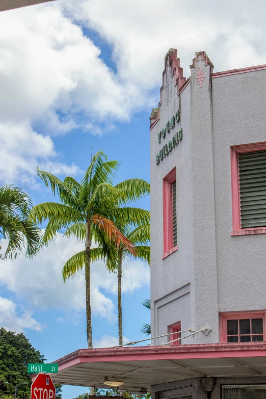 a red stop sign sits outside a building with palm trees