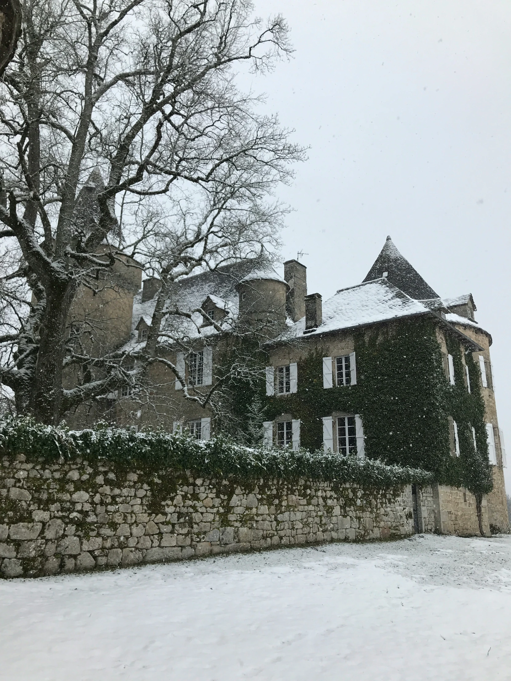 a large stone wall outside a home covered with snow