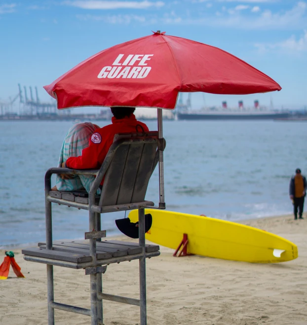 an umbrella in the sand next to a life guard chair