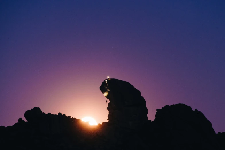the setting sun shines behind large rocks