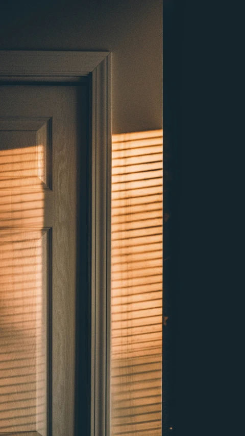 an open door has a light coming through the blinds