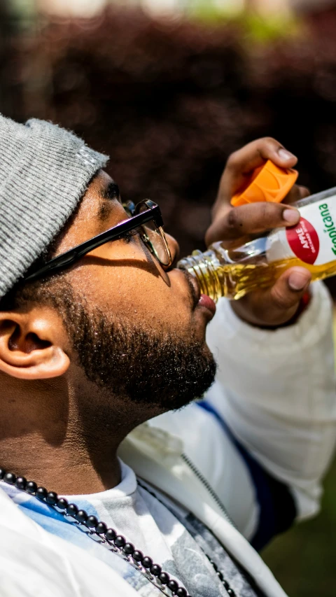 a man with glasses is drinking an orange juice