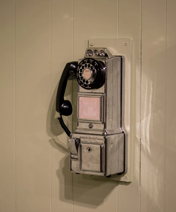 an old style phone is mounted to the wall