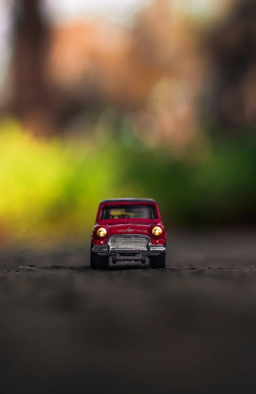 a red toy car that is on a asphalt ground