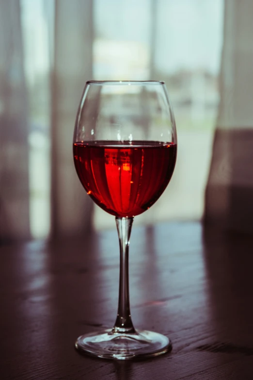 a red wine glass on a table with water inside