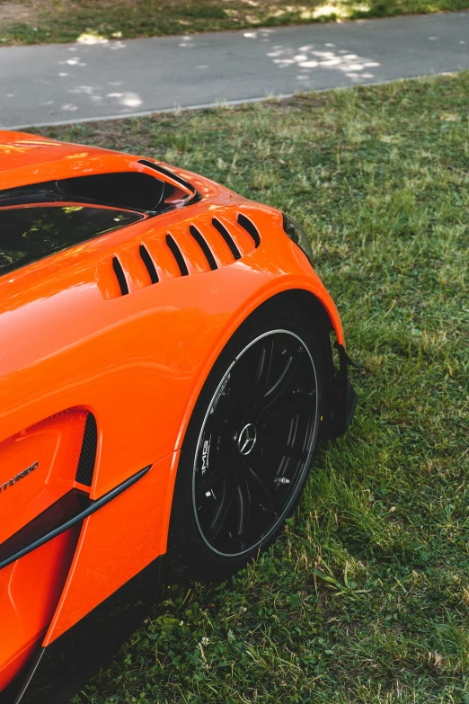 an orange sports car parked on the grass