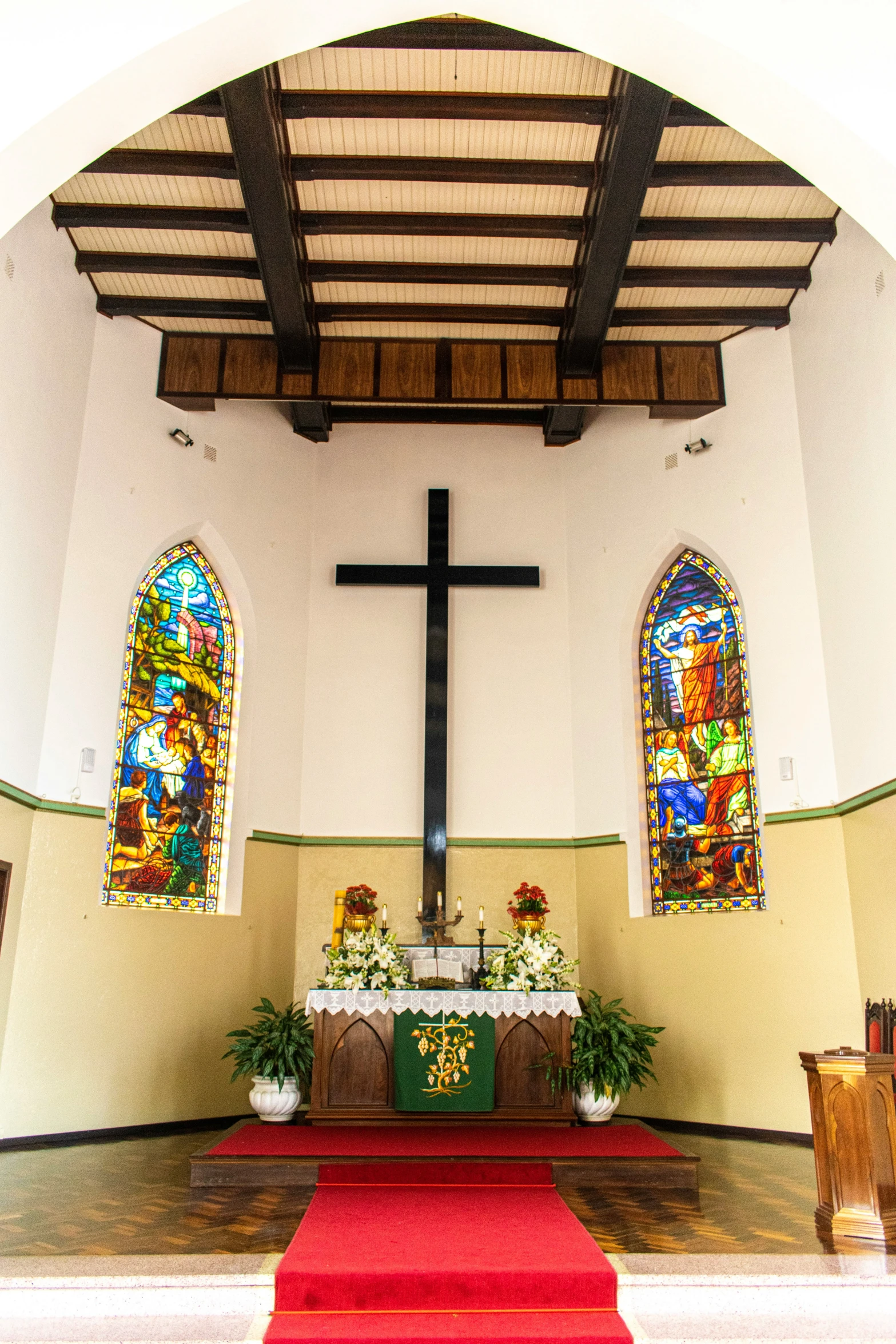 an arched room with a cross and flowers on the carpet