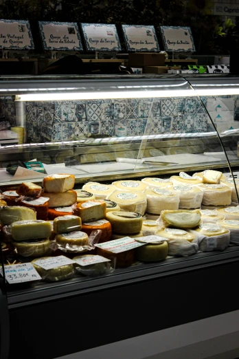 cheeses on display in a shop on a rack