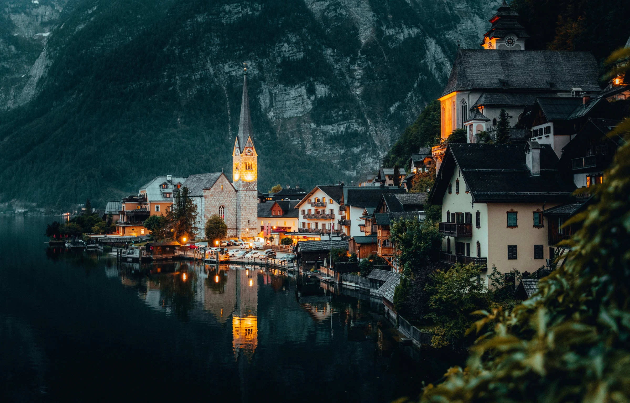 a village with steeples along a river with mountains in the background