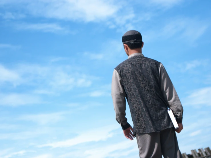 a man standing on top of a skateboard under a blue cloudy sky