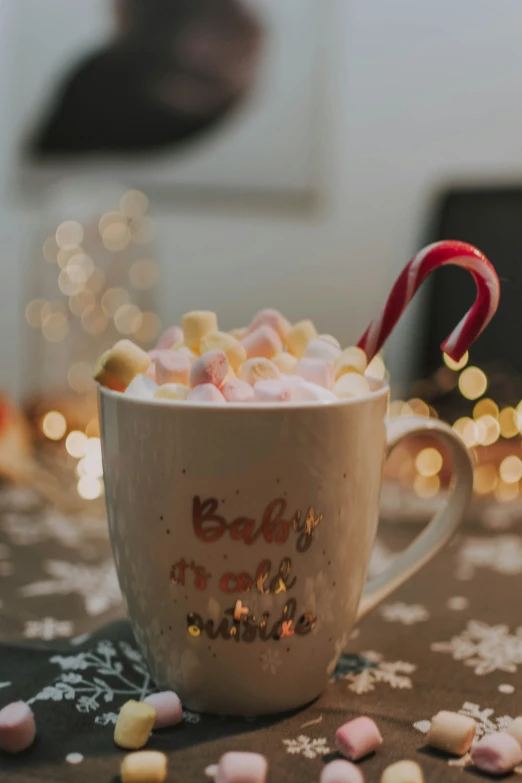 a cup with marshmallows, marsh and candy cane on top