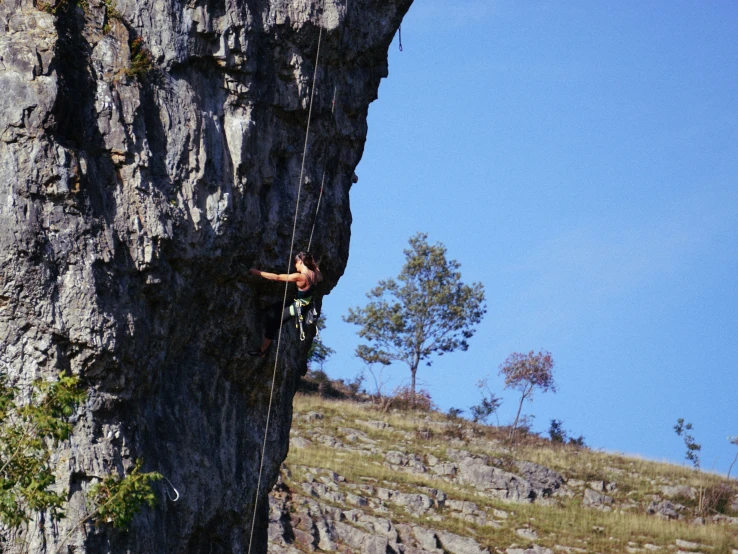 a person who is hanging from a rope attached to a rock