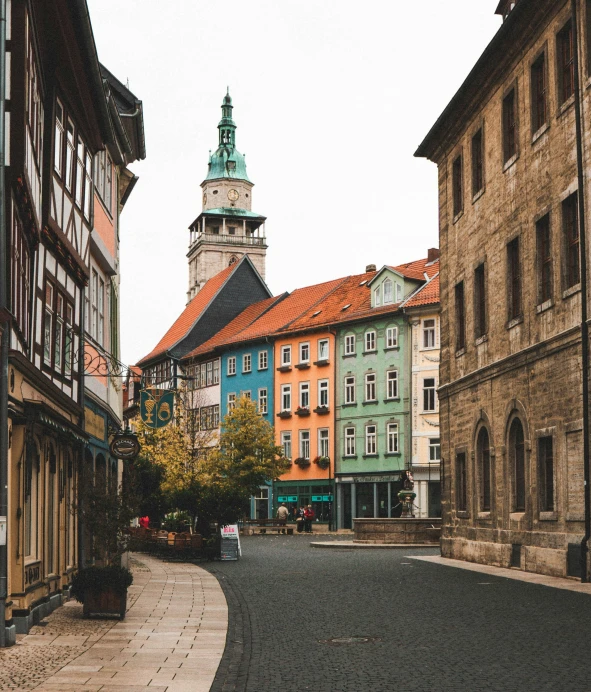 a small street with some buildings and a tower in the background