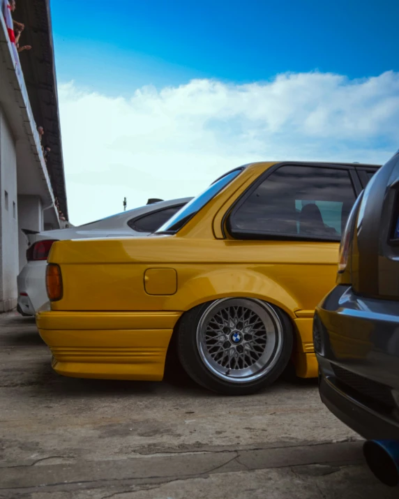 a yellow car parked next to another car in a garage