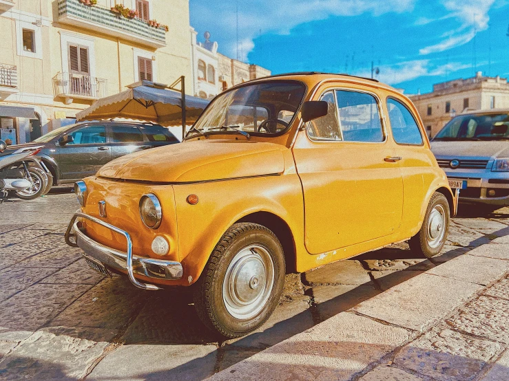 an old orange car is parked on the side of a street