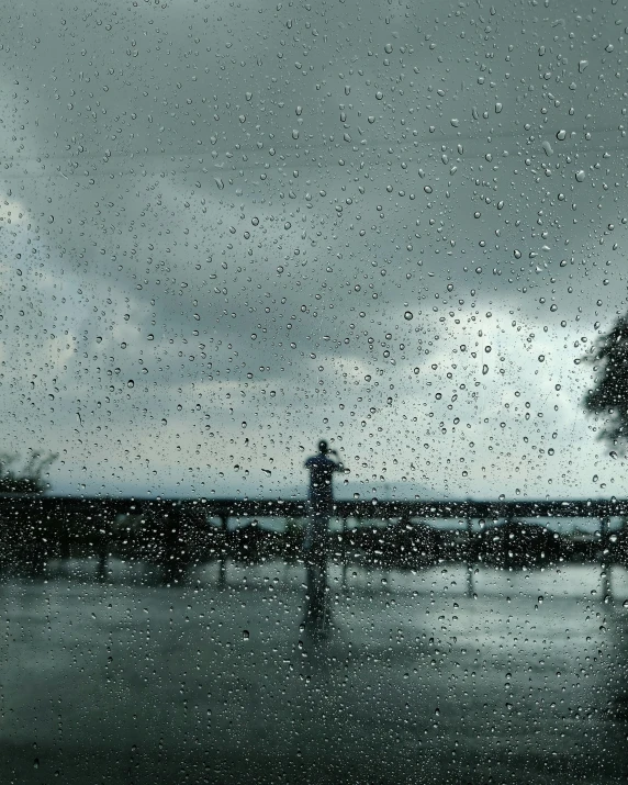 a man standing on a wet pier looking out at the ocean