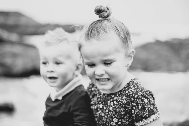 two children smile at the camera while one child looks on