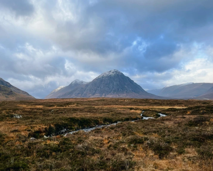 a mountain range in the background with a stream running between it