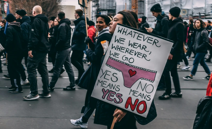 a woman holding a sign in the middle of a crowd