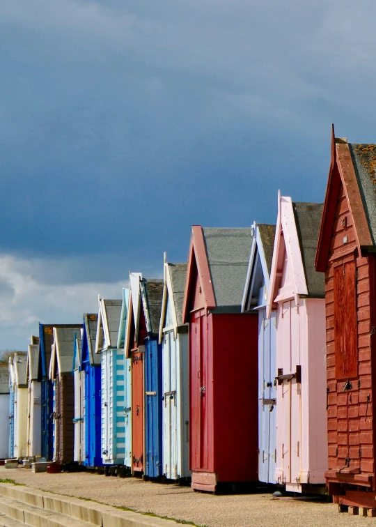 beach huts line the side of a pier next to the ocean