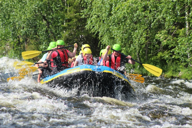 a group of people on an inflatable raft with green helmets