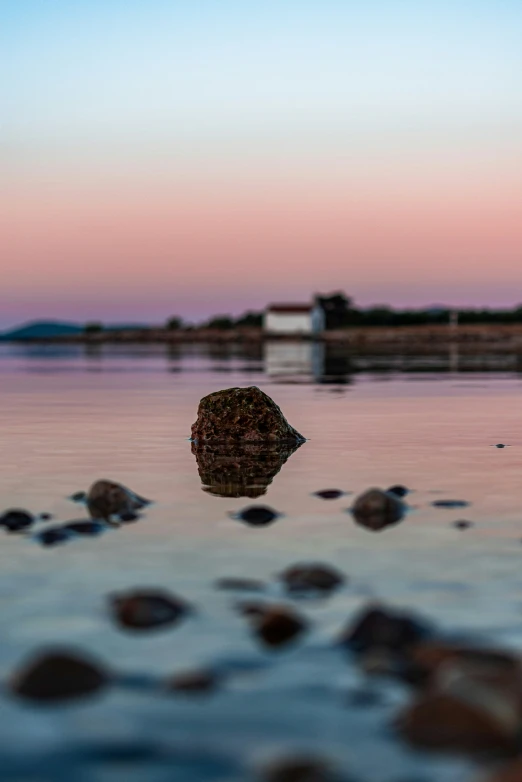 a rock in the water at sunset