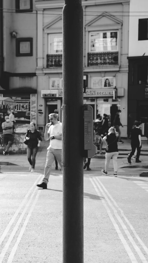 a black and white image of a woman walking in front of a bus stop