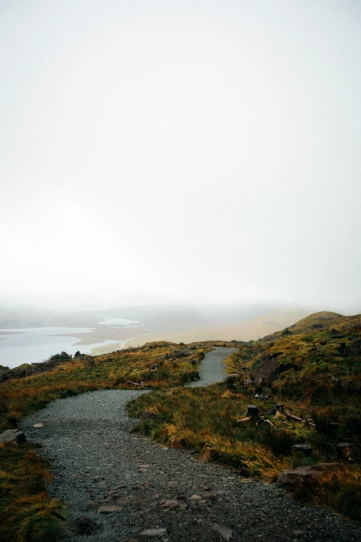 a pathway running up a grassy hill to a lake