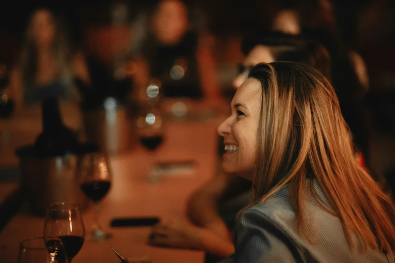 a woman sitting at a bar next to two wine glasses