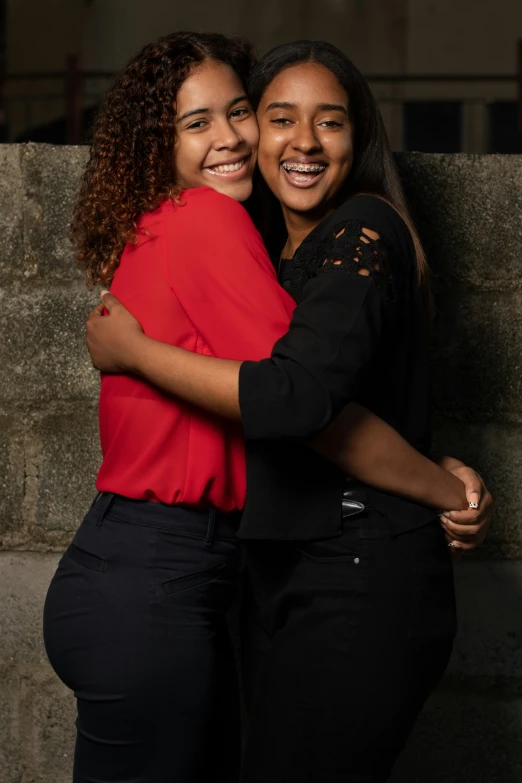 two people smiling and hugging in an outdoor setting