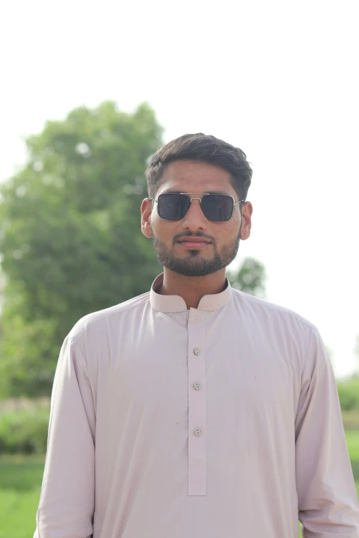 a man with a beard wearing shades and a pink top