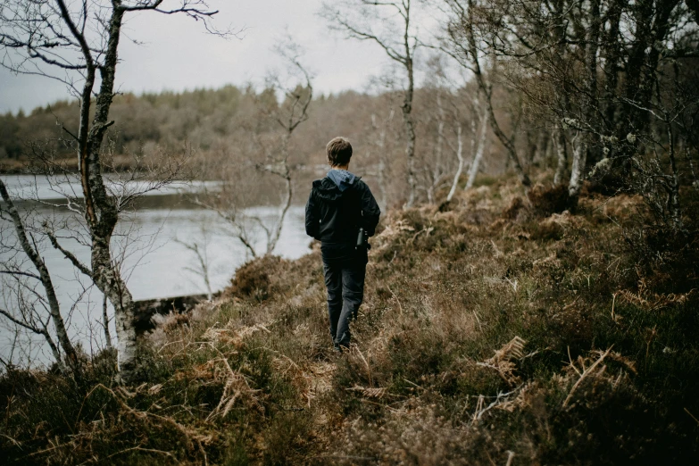 a person walking by some water next to a field