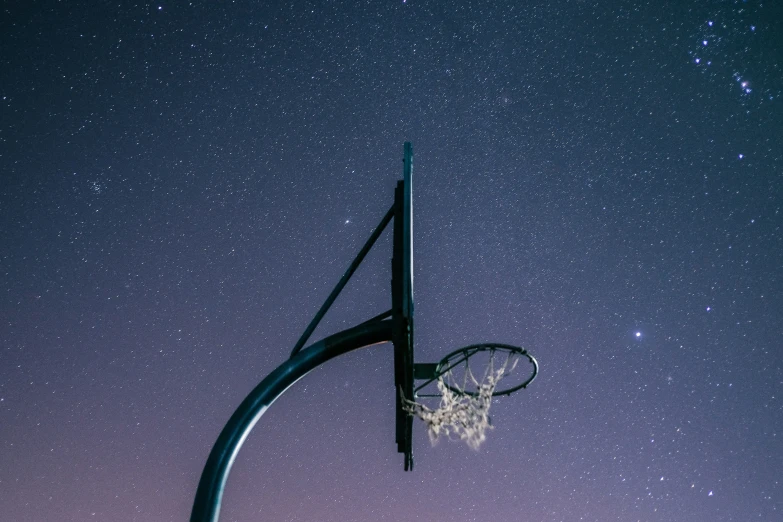 a basketball hoop attached to a basketball goal under the night sky