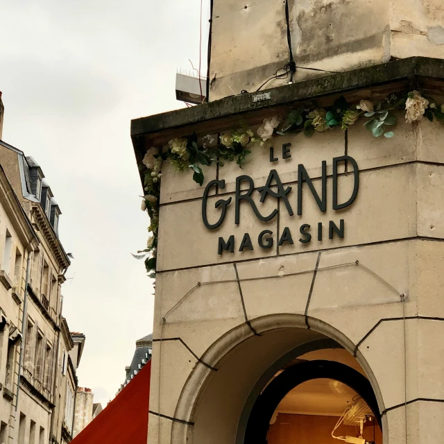 a street sign reads grand magasin next to a building with red brick